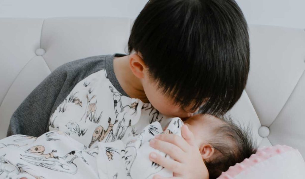 Adjusting to change: older brother kissing baby brother on the forehead